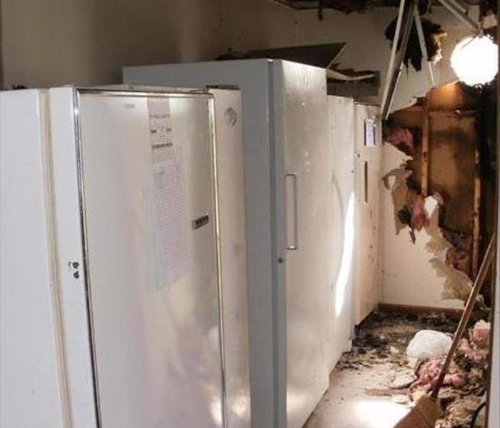 broom on floor, broken wall and ceiling with a charred wall void